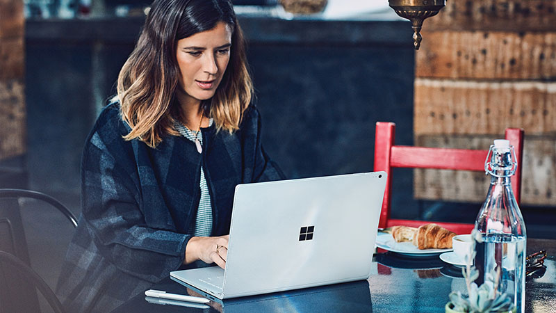 Woman sitting at cafe table with Surface