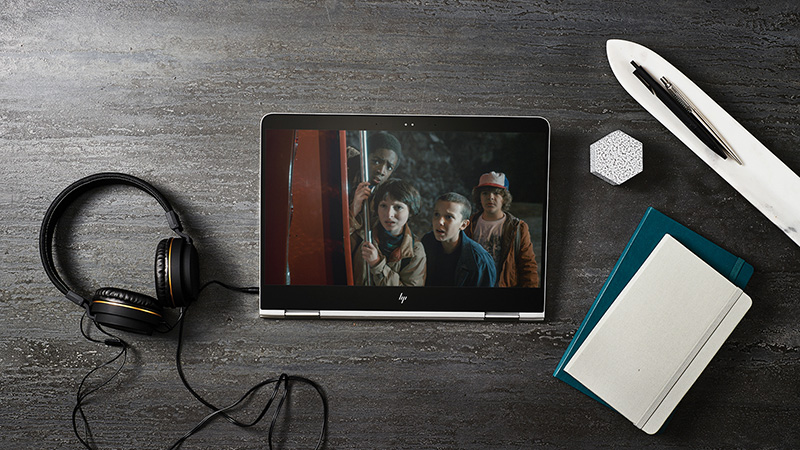 Tablet laying on table next to headphones and books